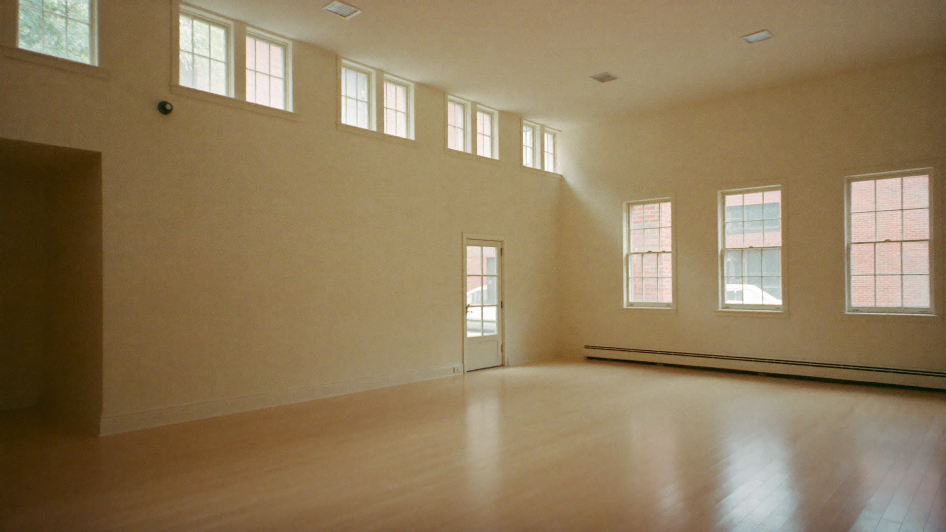 A bright, empty community hall with tall windows and a pale timber floor